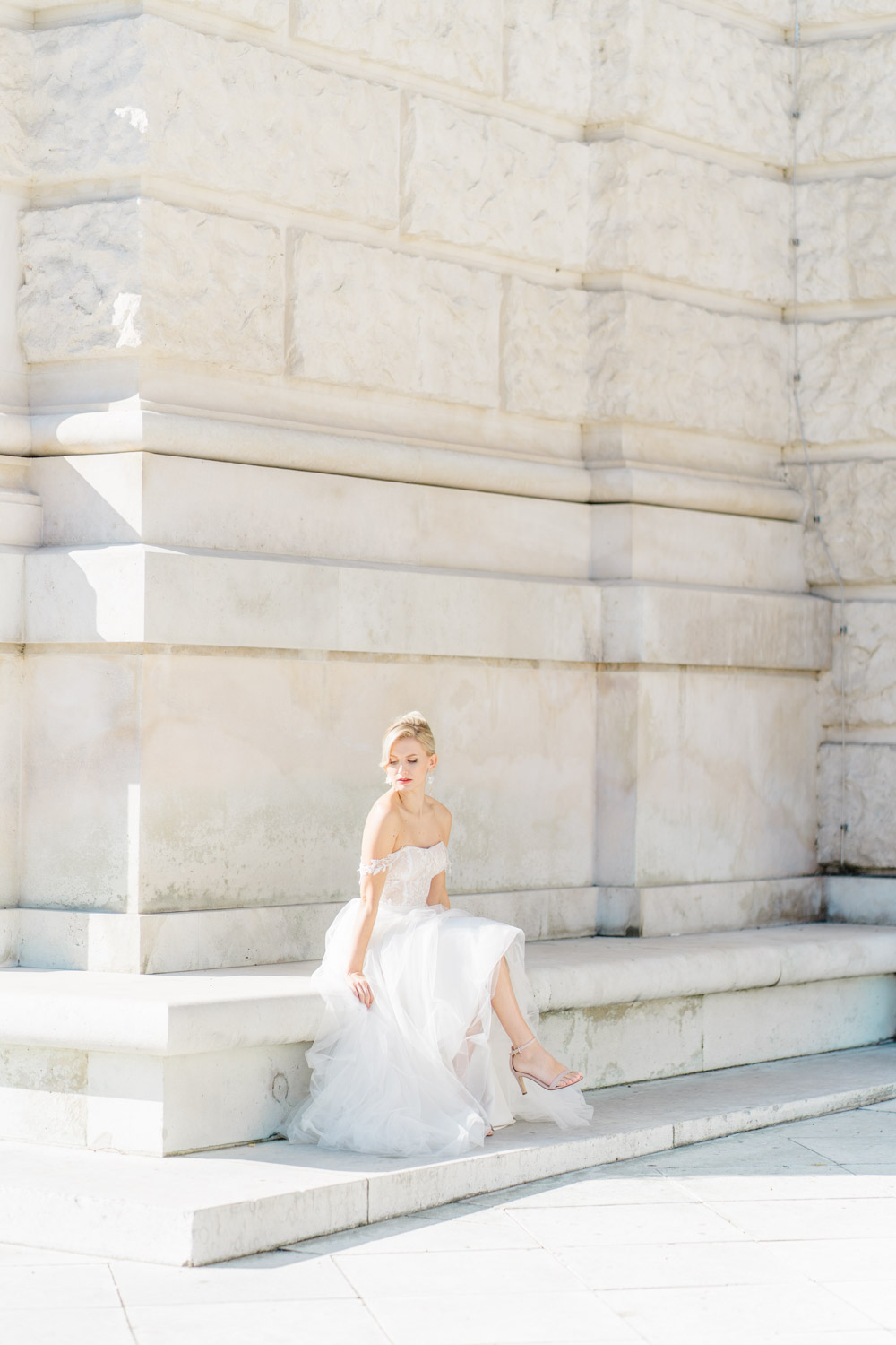 Hochzeitsfotograf Wien: Eine Braut sitzt auf einer Mauer vor der Hofburg.