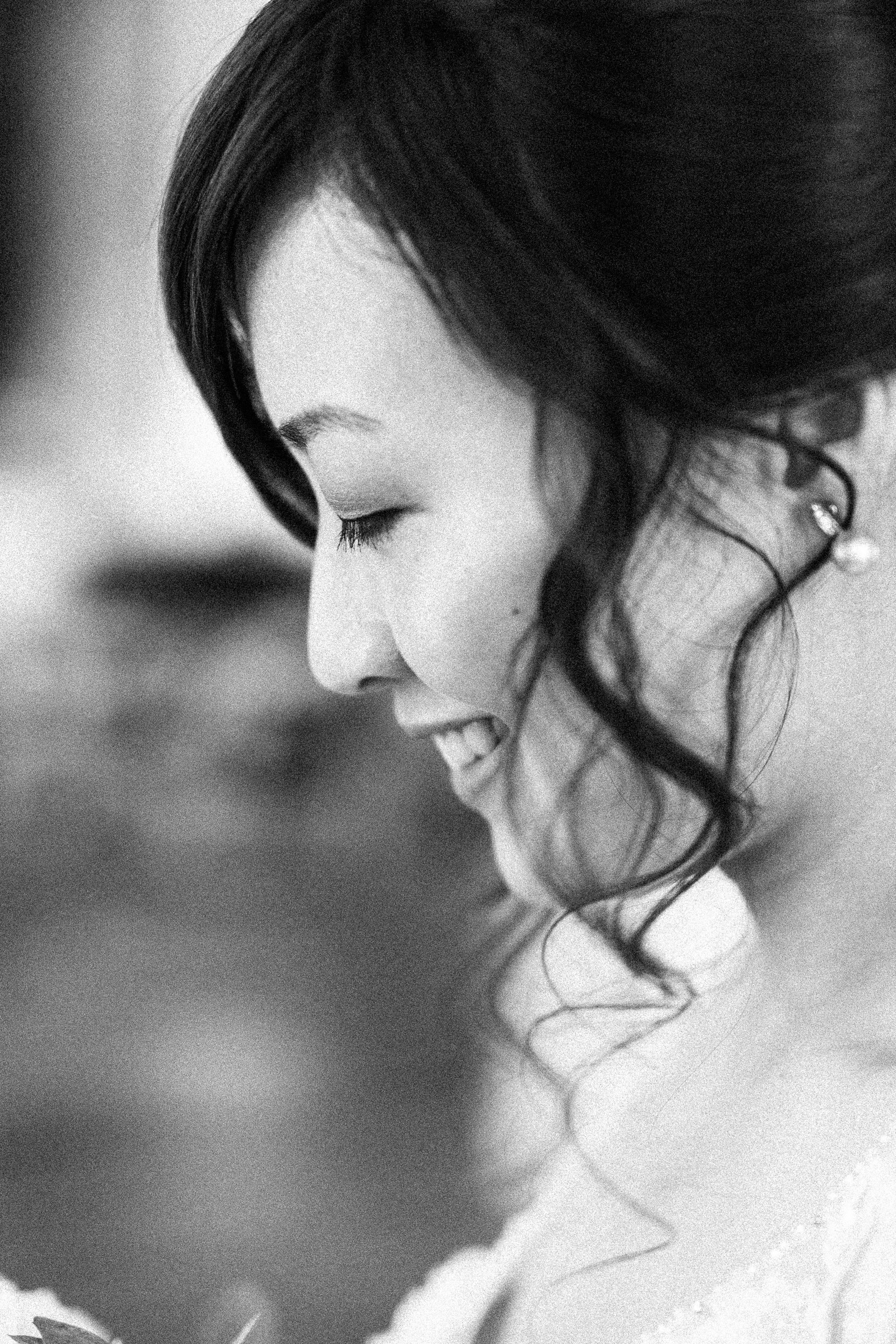 Hochzeitsfotograf Wien: Close-up Portrait einer dunkelhaarigen Frau im Profil, die mit geschlossenen Augen lächelt.