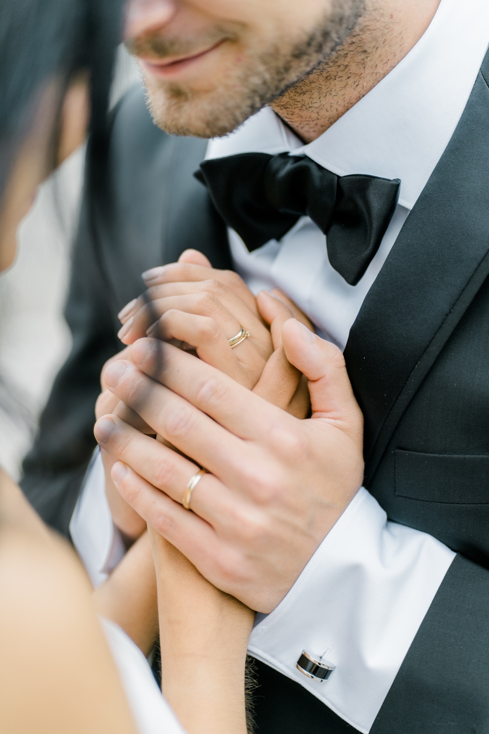 Hochzeitsfotograf Wien: Detailaufnahme von sich umschlingenden Händen mit Eheringen.