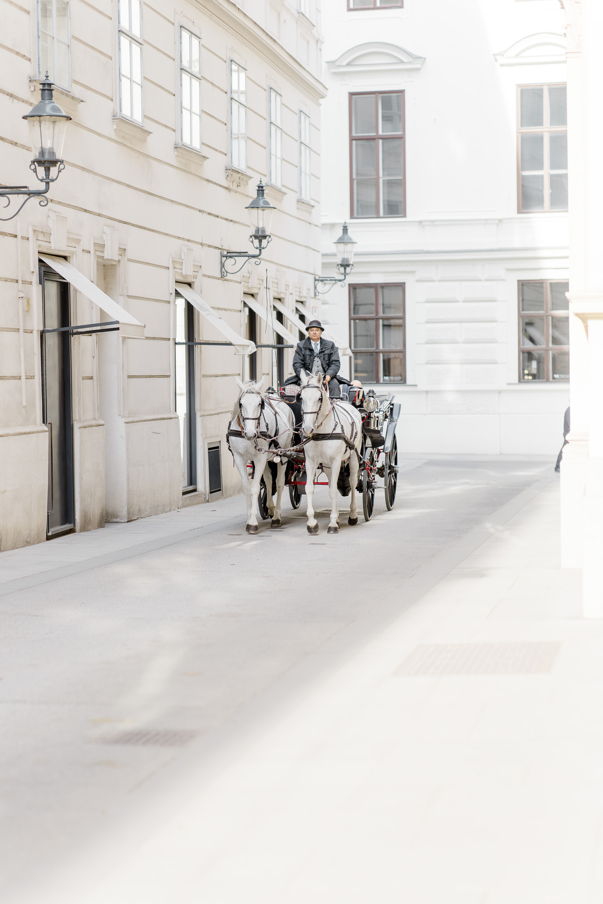 Hochzeitsfotograf Wien: Ein Fiaker fährt durch eine helle Altstadtgasse.