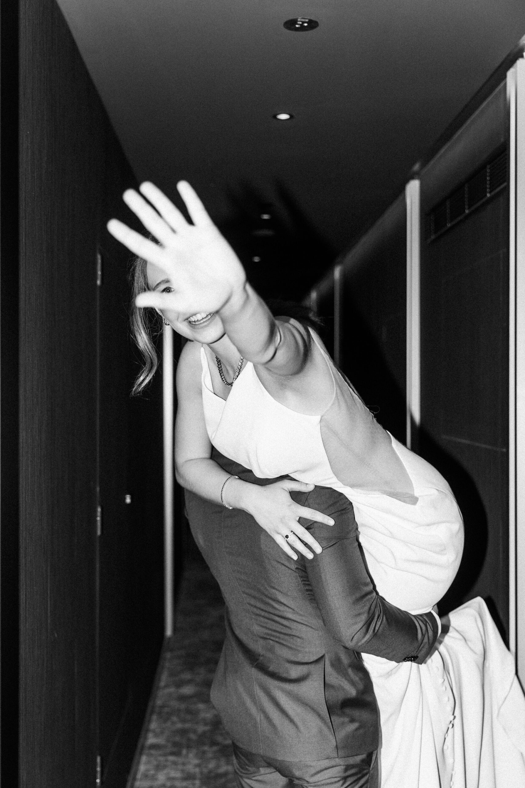 Hochzeitsfotograf Wien: eine lachende Braut wird vom Bräutigam getragen und streckt die Handfläche in Richtung Kamera.