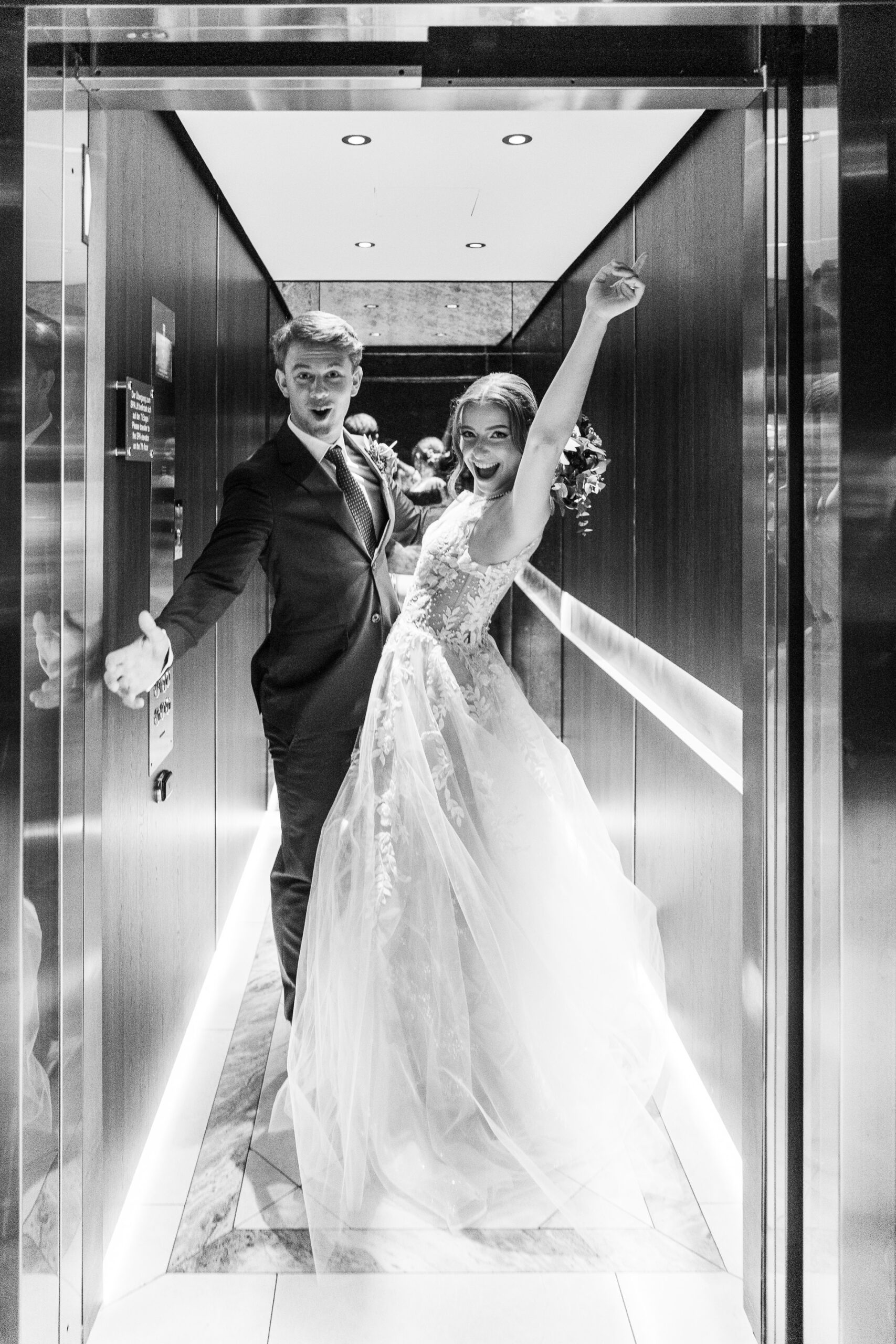Hochzeitsfotograf Wien: Ein jubelndes Brautpaar steht in einem offenen LIft im Palais Almanac.