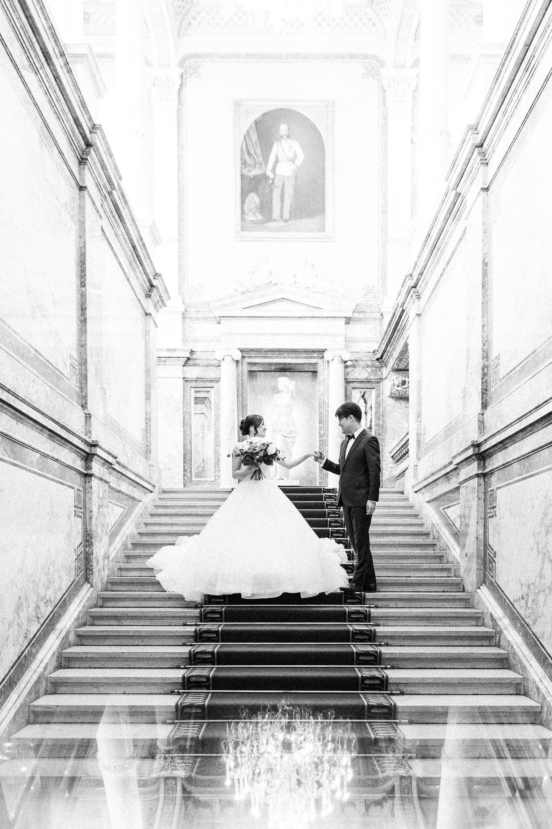 Hochzeitsfotograf Wien: ein Brautpaar in eleganter Kleidung steht auf der Fürstenstiege im Hotel Imperial.